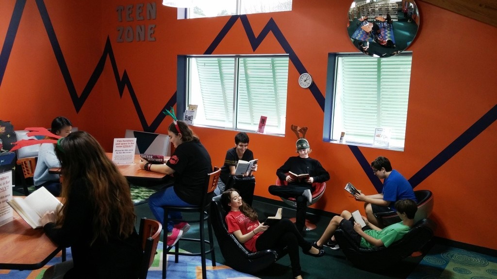 VolunTeens and teen patrons enjoying the revamped teen area which has doubled in size and been furnished with three high-top tables, chairs and bench seating.