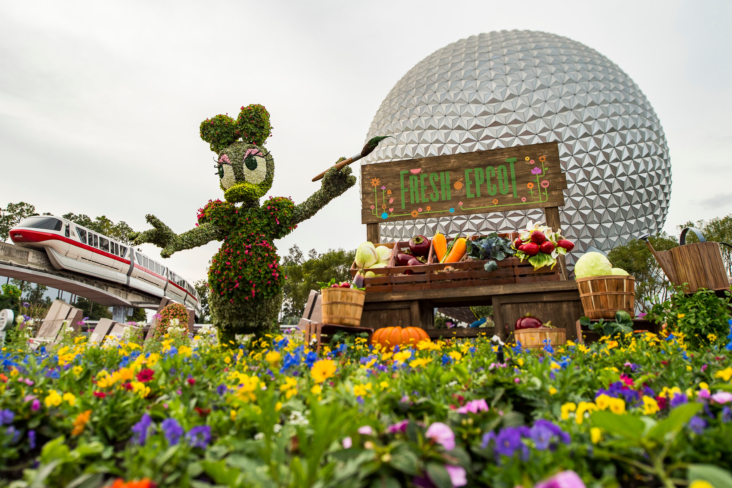 Daisy Duck in topiary form poses by a colorful garden at Epcot