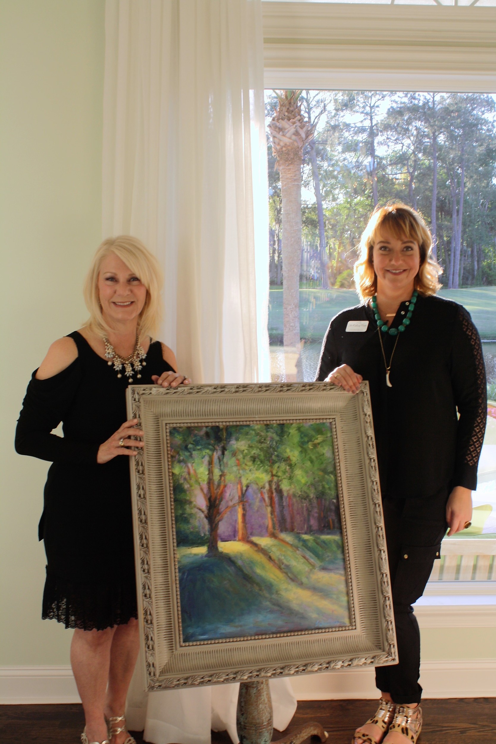 Susan Woodburn displays one of her paintings to Cultural Center Development Director Toni Boudreaux at the Sunset & Tapas event.