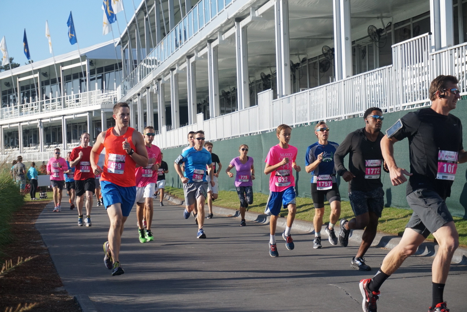 The first wave of participants in the PLAYERS Donna 5K races along the cart paths by the newly renovated double-decker hospitality buildings