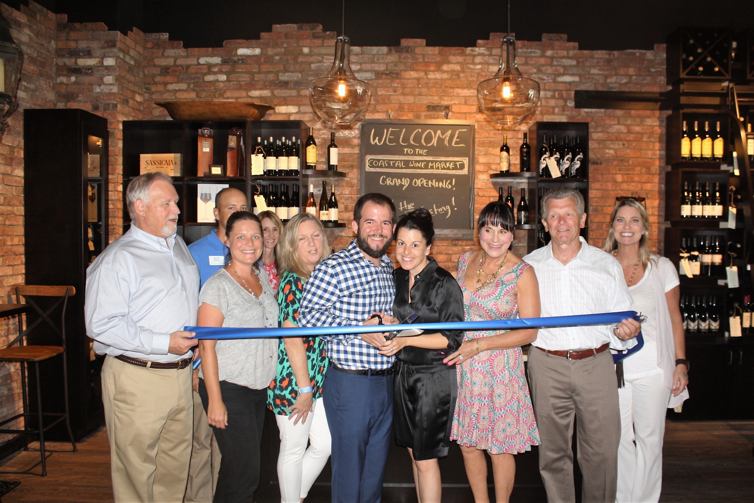 Steve and Shaun Lourie (center) cut the ribbon on their new Nocatee business, Coastal Wine Market.
