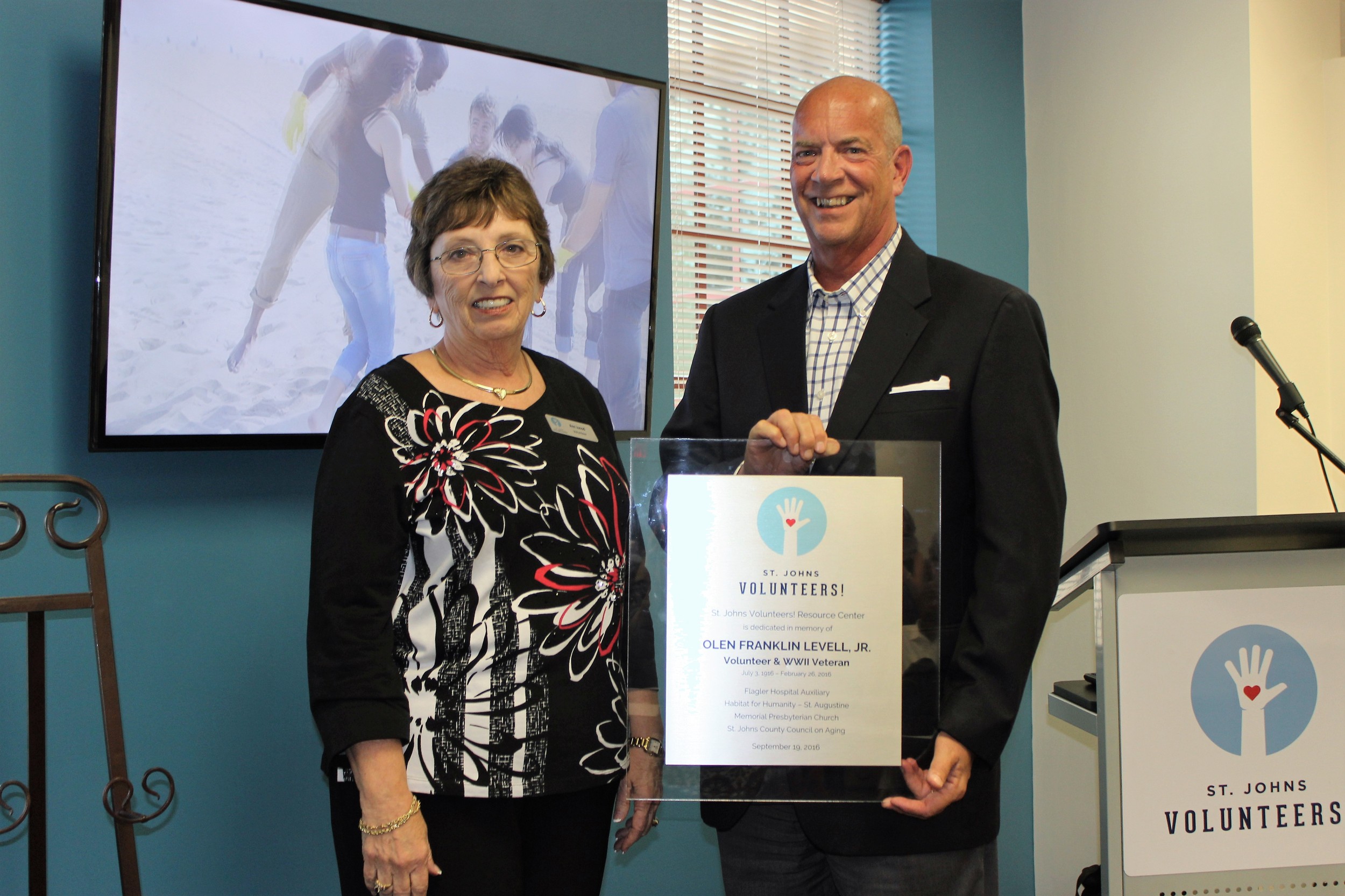 Flagler CEO Joseph Gordy (right) presents Ann Junod with an award recognizing her late father's volunteer services.