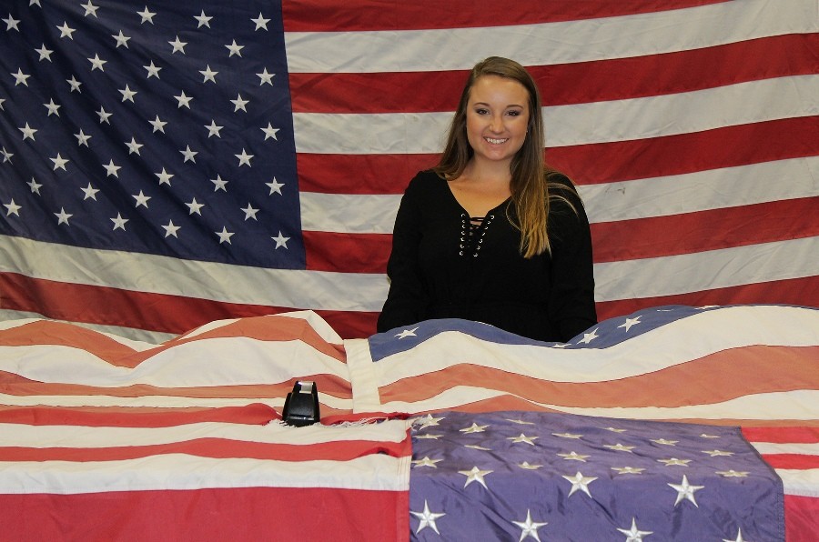 Advanced Disposal intern and flag retirement program collection coordinator Amanda Holsinger with a few of the flags collected for honorable retirement