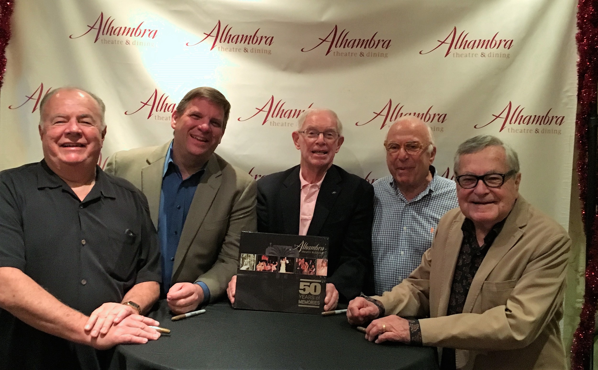 Three generations of Alhambra Theatre & Dining owners gather for a book signing marking the release of “The Alhambra Theatre & Dining: 50 Years of Memories.” From left: Former owner and current director Tod Booth, current owner and Managing Partner Craig Smith, author Charles Day, and original owners Ted Johnson and George Ballis.