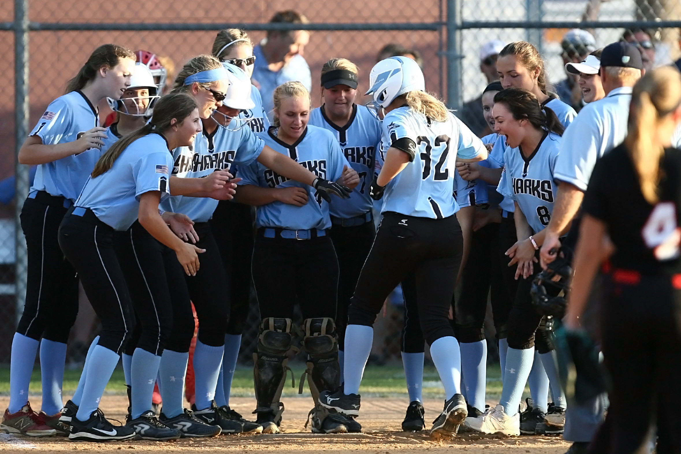 Sharks welcome #32 Farley Callaghan at the plate after her two-run home run.