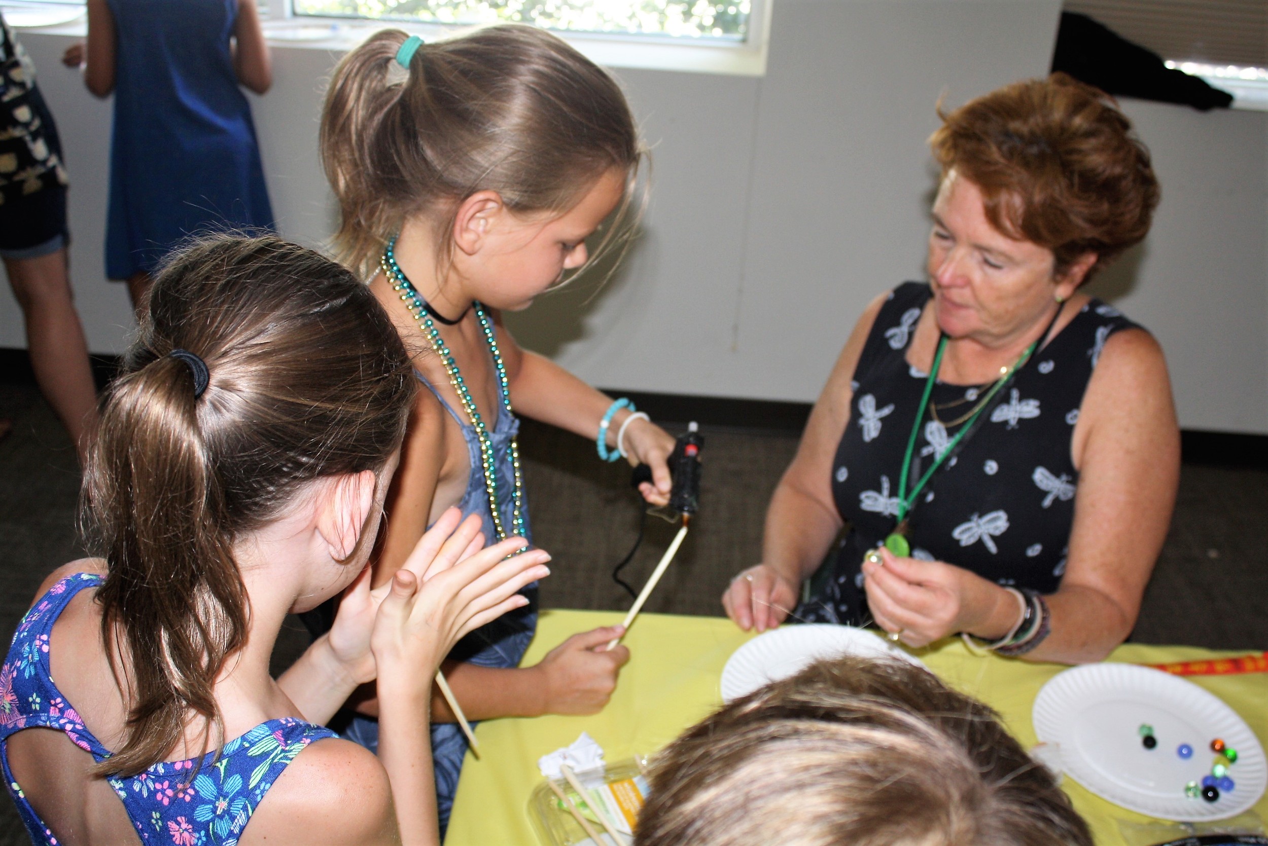 Youth Services Assistant Suzanne Egeln (right) helps children make magic wands.