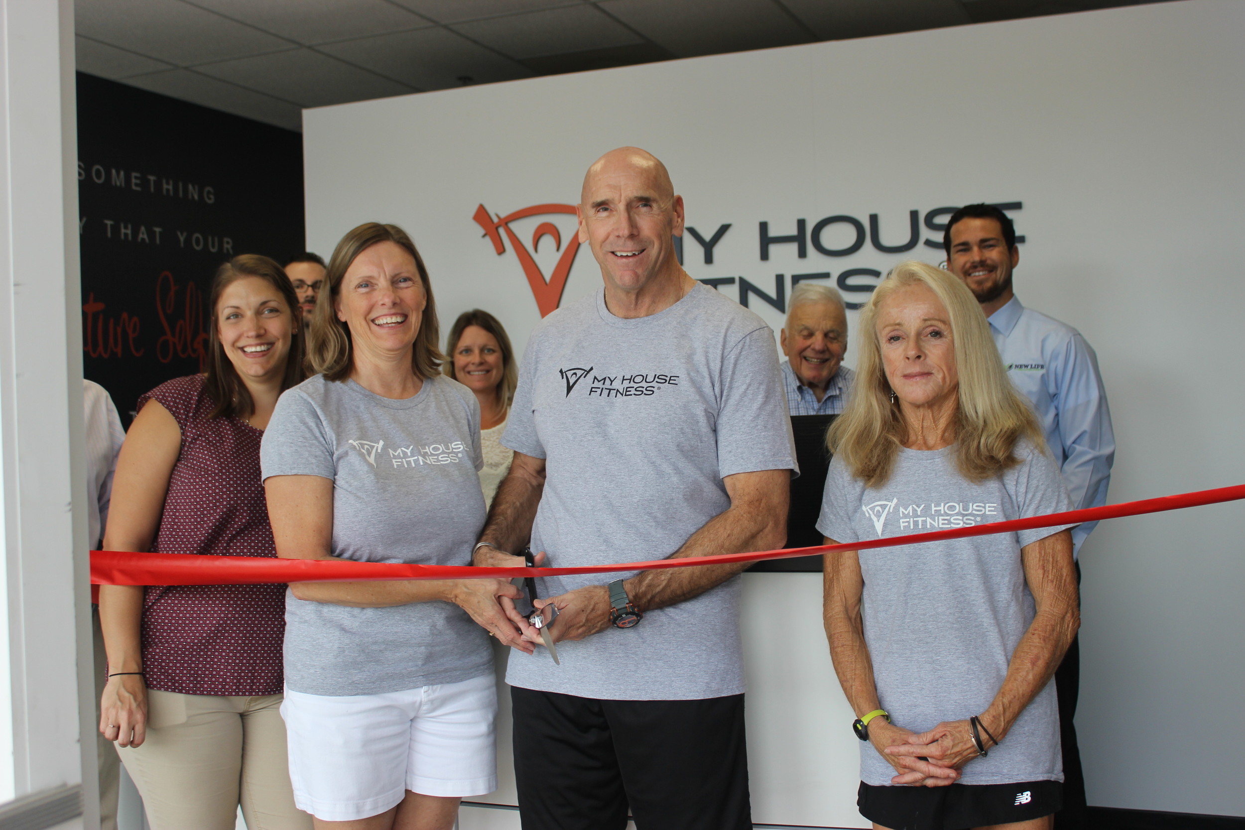 The My House Fitness team participates in a ribbon cutting ceremony as part of its grand opening event.