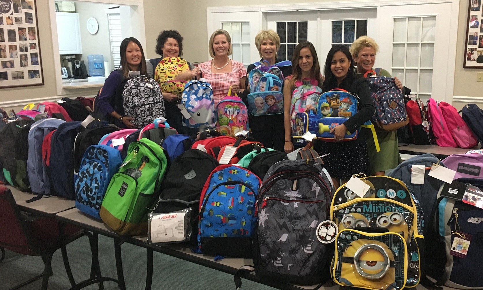 Marisa Mariano, Marian Snovell, Christy Budnick, Linda Sherrer, Brenna Antram, Chantha Bisher and Maria Wilkes hold backpacks donated to Berkshire Hathaway HomeServices Florida Network Realty’s 18th annual Backpack Challenge.