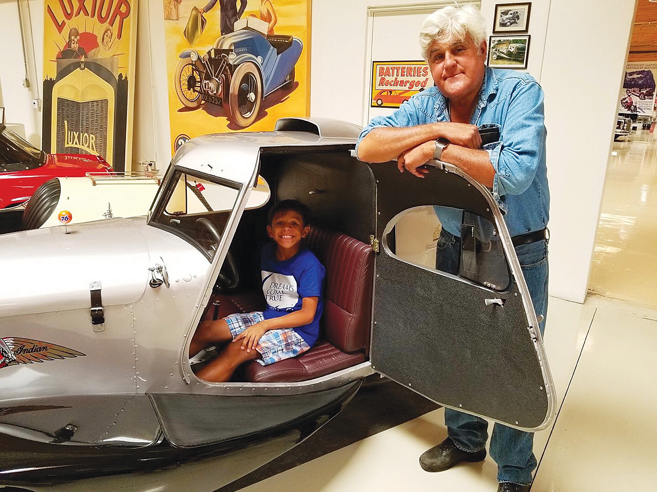 Jake McGuire sits in one of Jay Leno’s classics with the television icon standing by his side.