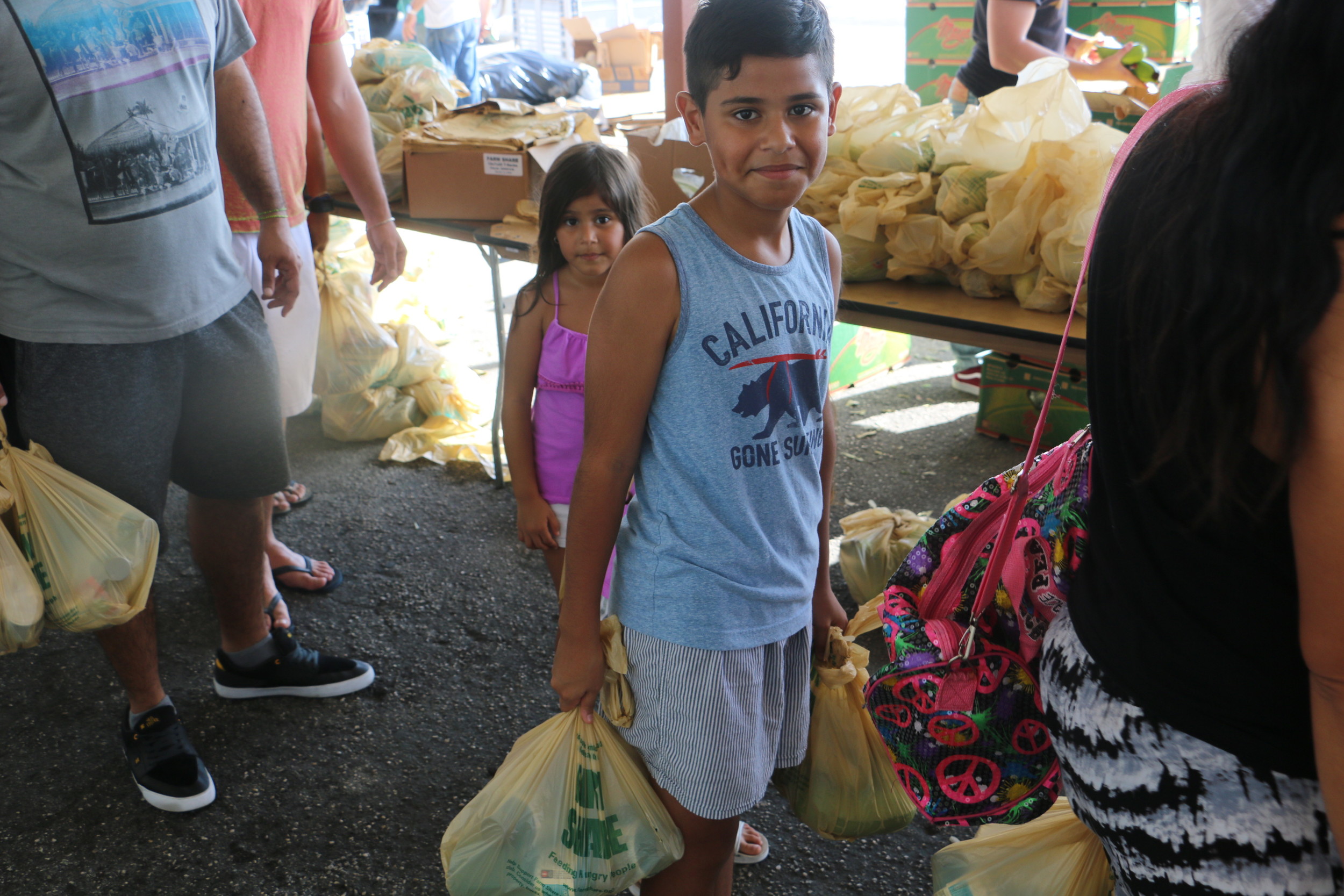 A child carries supplies provided by Farm Share to help residents in the wake of Hurricane Irma.