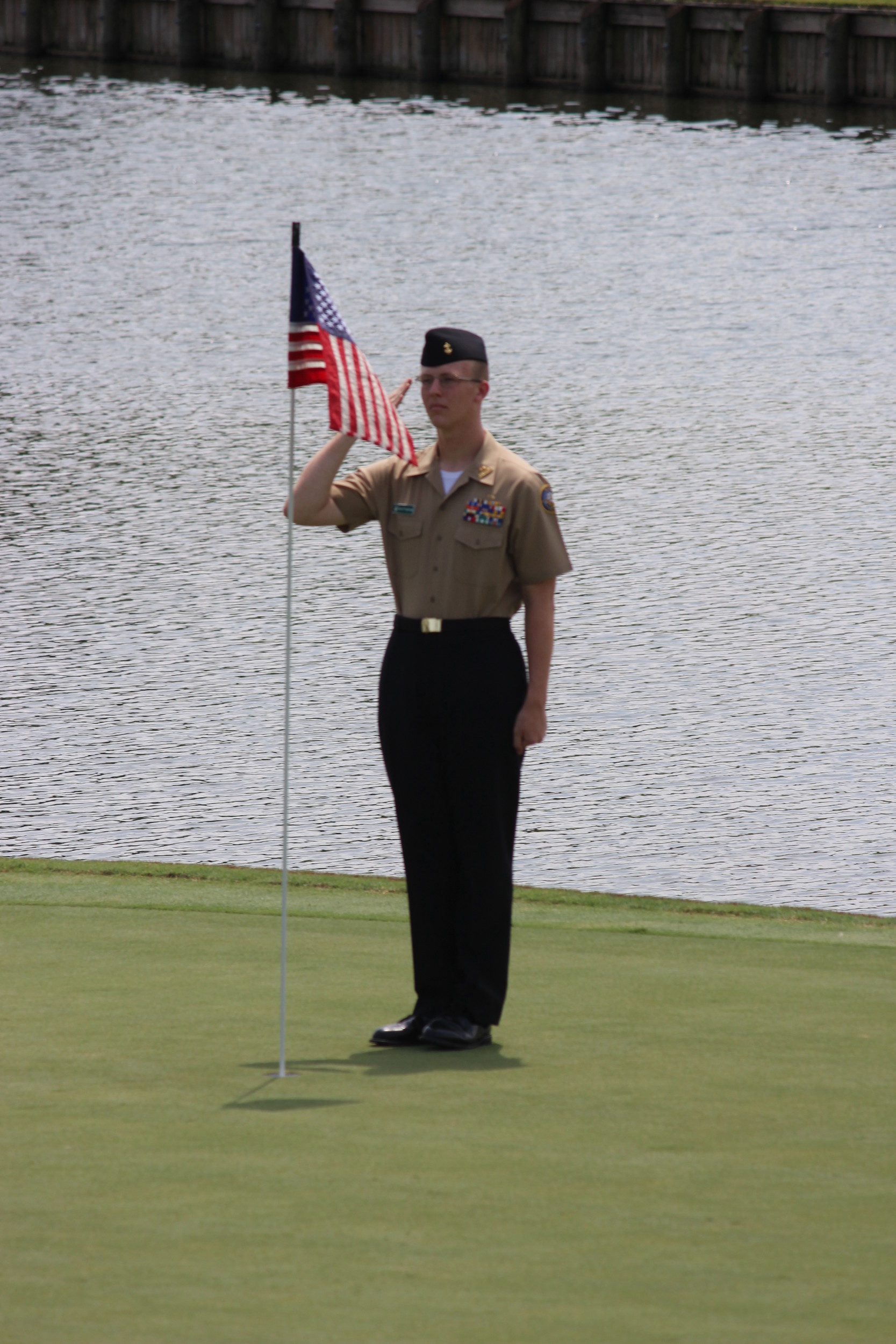 Cadet Konnor Matthews salutes the American flag on the 18th hole during the American Junior Golf Association tournament over Labor Day weekend.