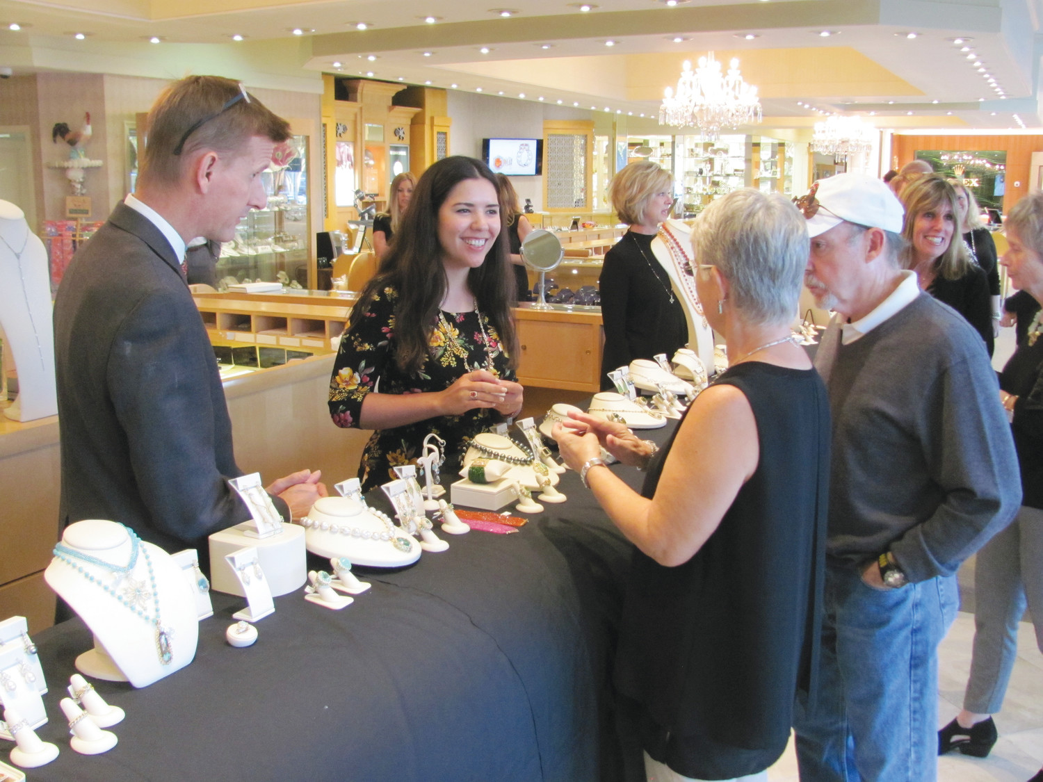 Underwood's Jewelers employees show trunk show attendees various pieces of Erica Courtney's jewelry.