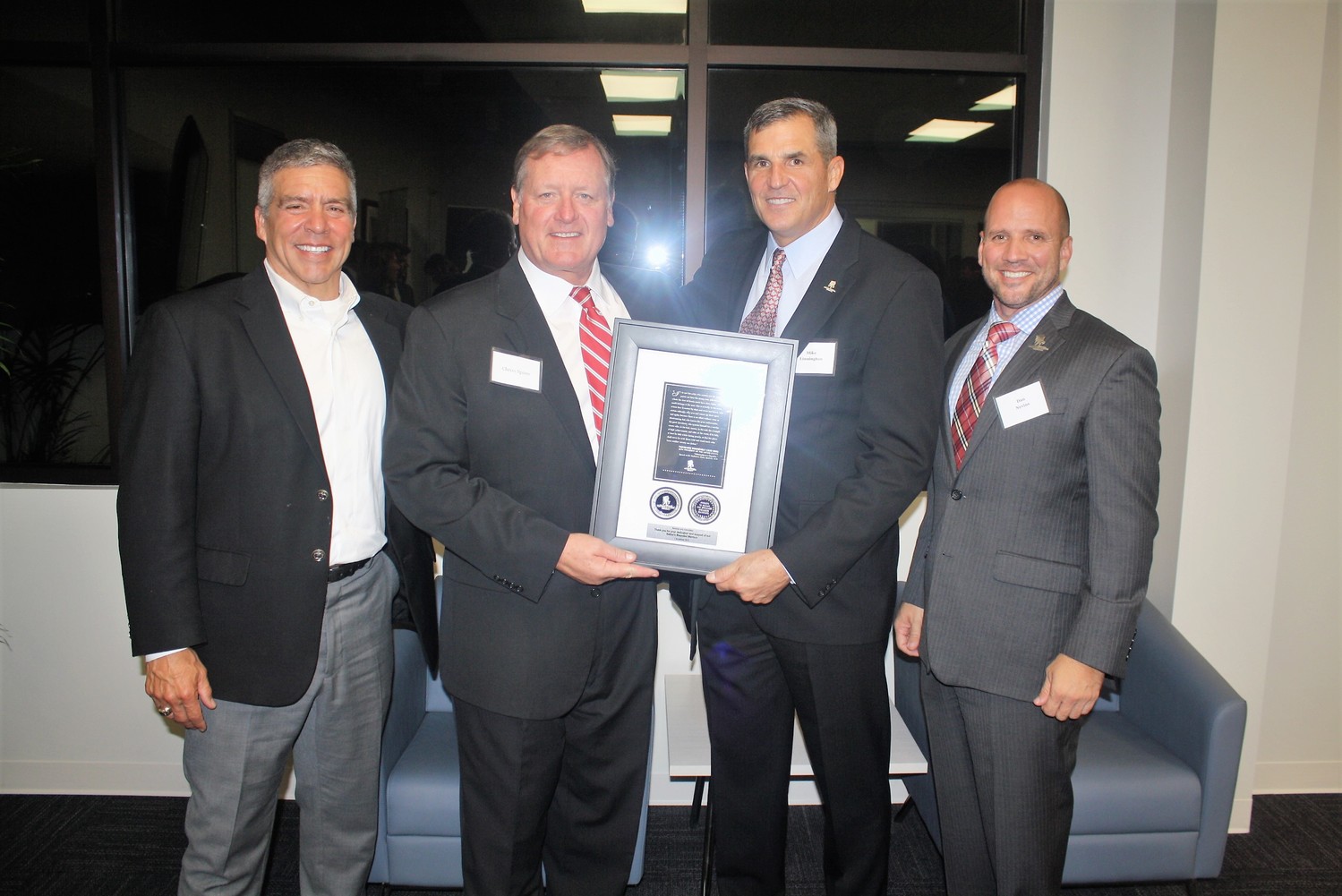 Wounded Warrior Project CEO Mike Linnington (center right) and Staff Sgt. Dan Nevins (right) present Montoya & Associates Principal Owner and Founder Will Montoya and Principal and Senior Advisor Chriss Spires with a commemorative plaque.