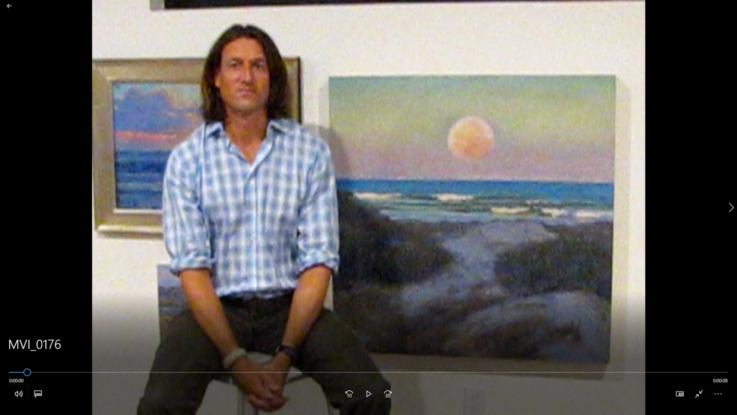 Quinn sits near his painting of the moon over the ocean at the Guana Preserve.