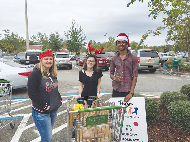 Olivia Ross (Creekside High School), Allie Venturi (Nease High School) and Mohammad Alam (Nease) collect food for Hugs Across the County’s “No Hungry Holidays” food drive.