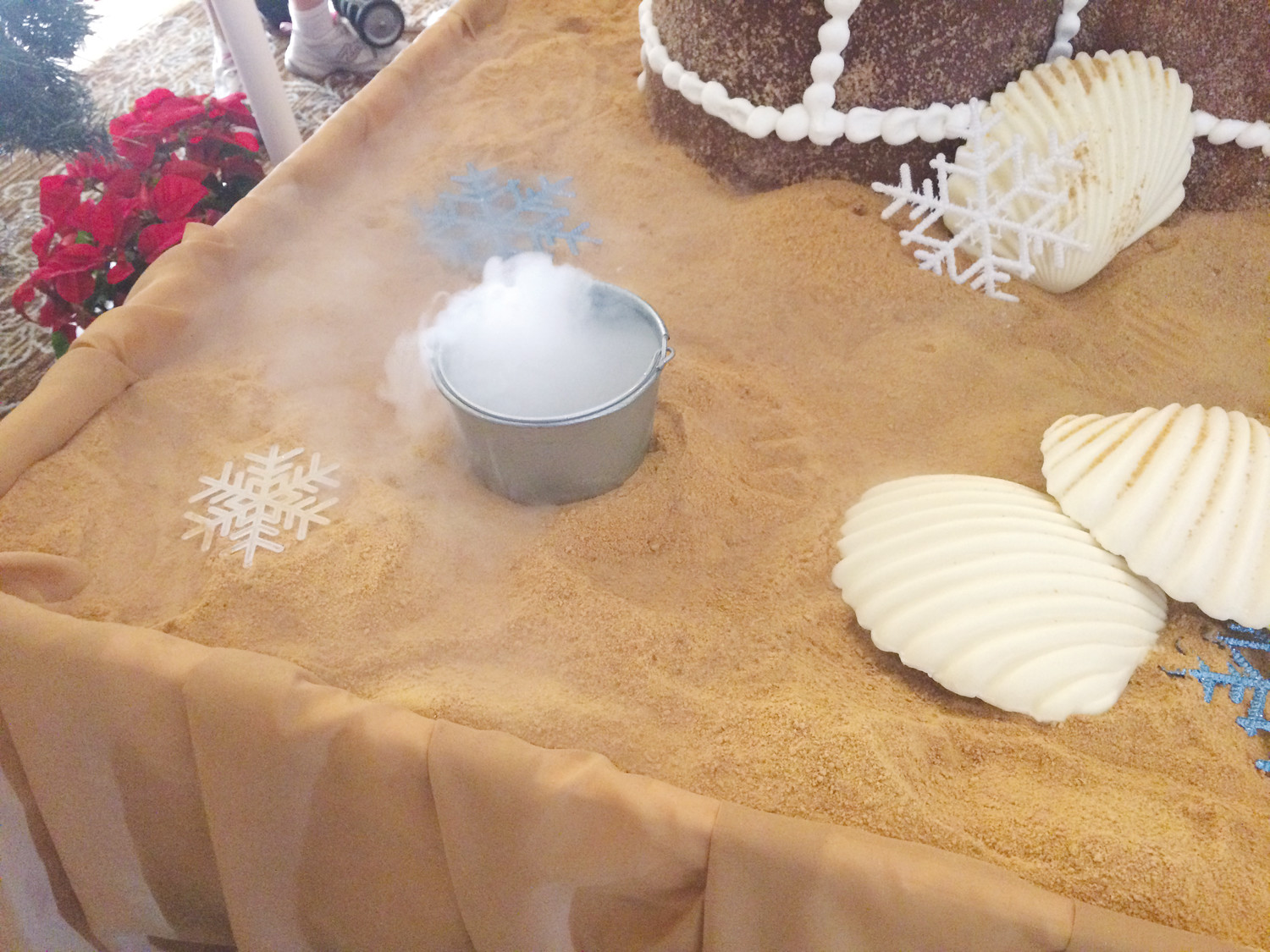Dry ice oozes out of a silver bucket near the gingerbread castle.