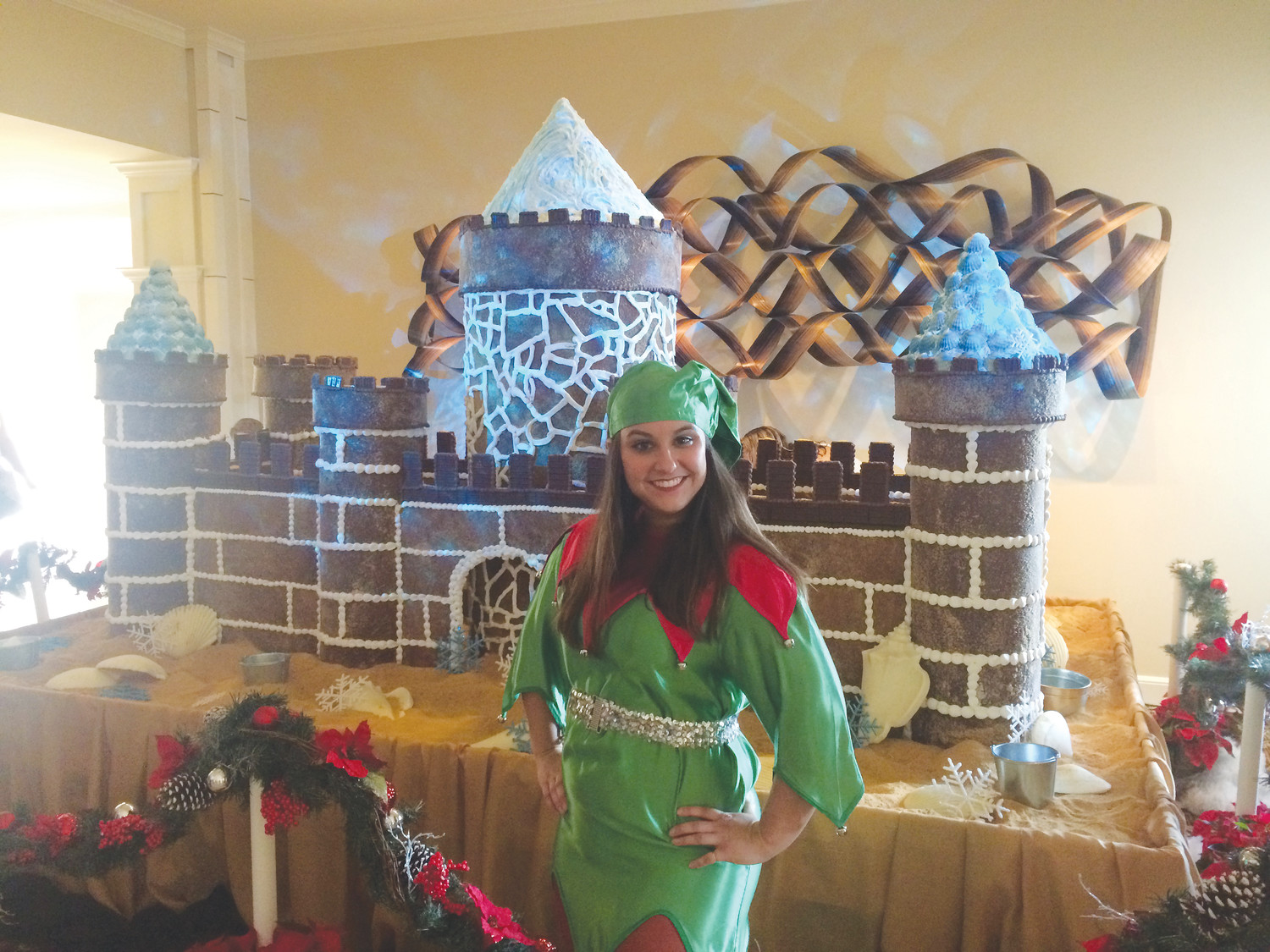 A One Ocean Resort & Spa employee dressed in Christmas attire poses for a photo in front of the gingerbread castle.