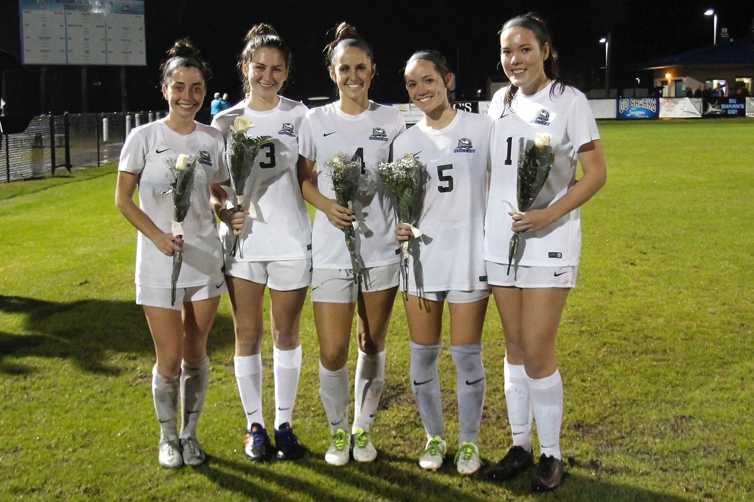 The five Shark seniors pose with roses. Left to right: Molly Miller, Leah Cills, Piper Dotsikas, Tatum Taucher and Katie Beman.