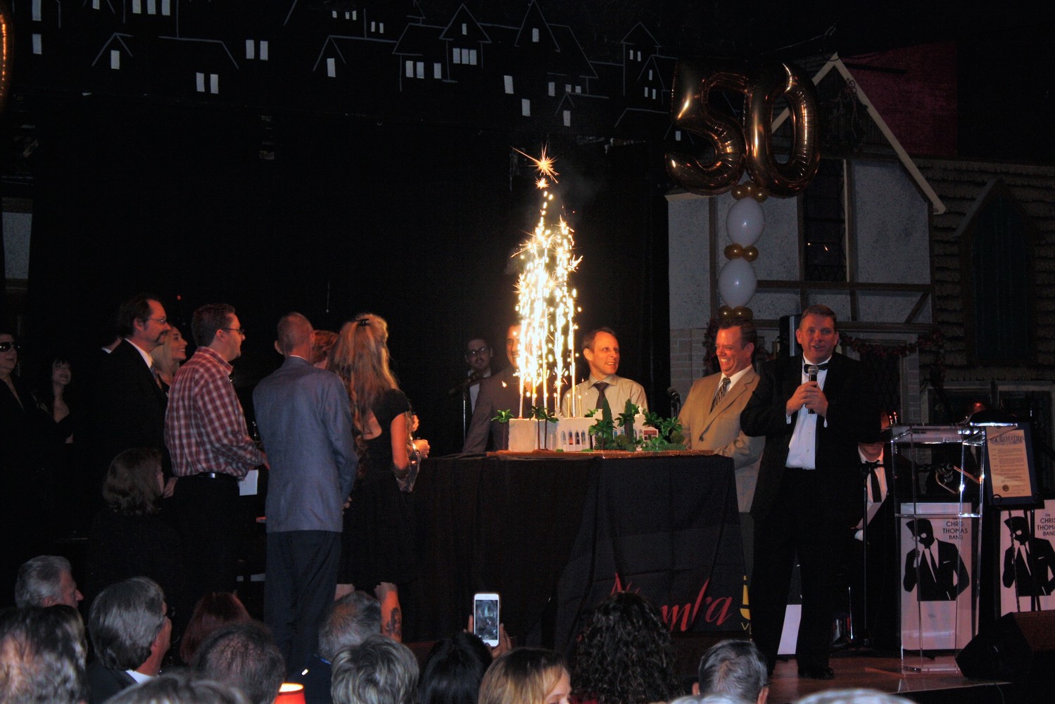 Alhambra staff gathers on stage to light the birthday cake's sparkler candles.