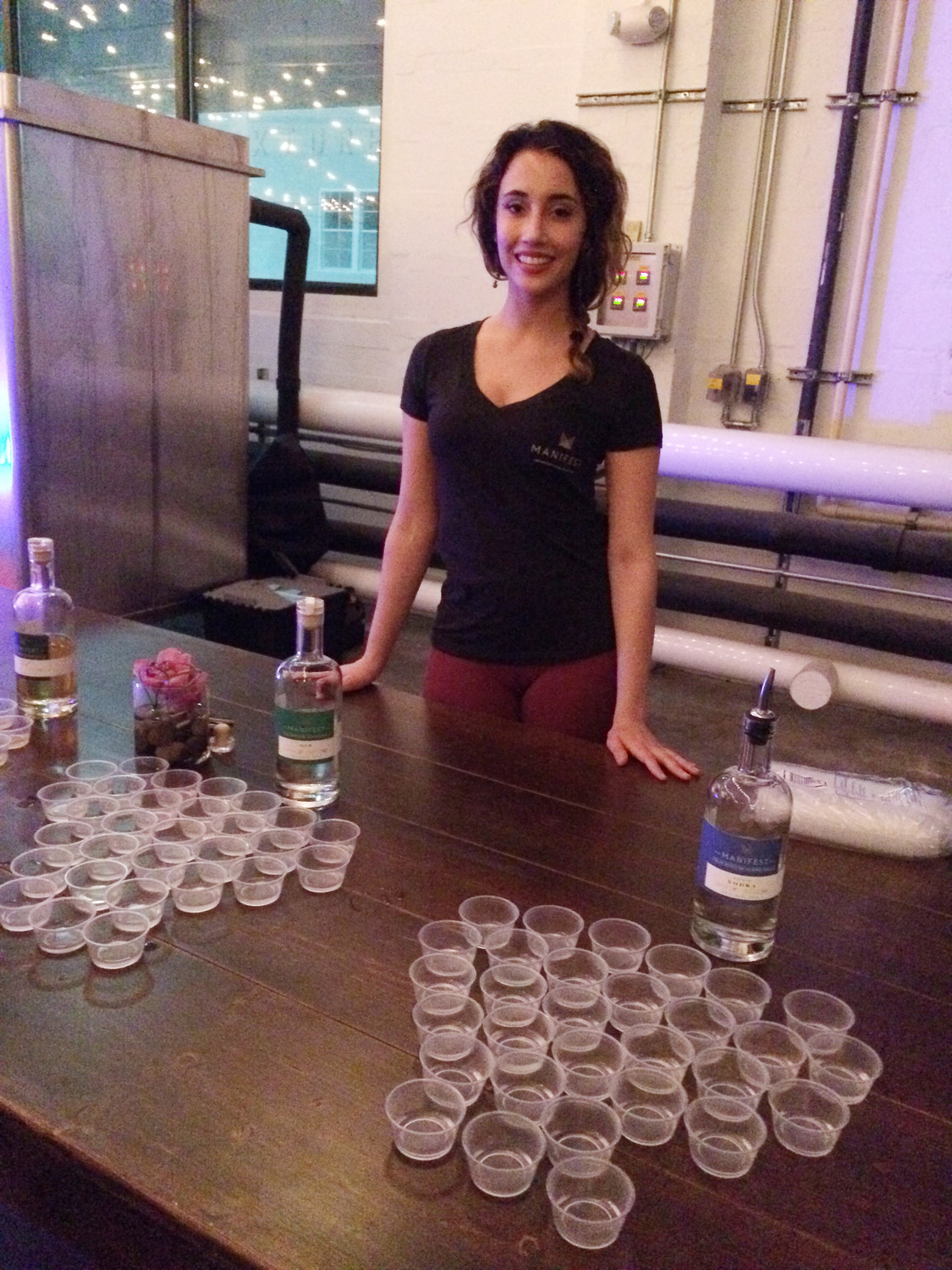 Ilsa Gehman poses for a photo behind drinks for Bowtie Ball guests at Manifest Distilling in Jacksonville.