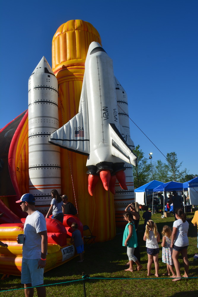 Kids line up to play on an inflatable slide at the Roscolusa Songwriters Festival.