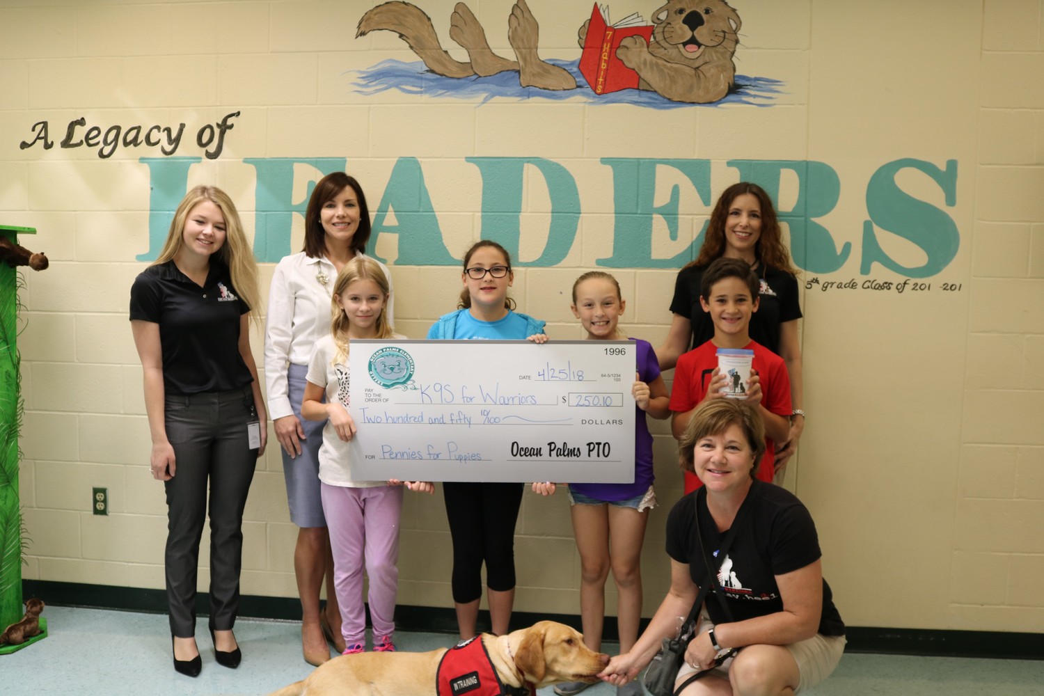 OPES students and staff present a check for $250.10 to K9s for Warriors after holding a fundraiser at a recent book fair.