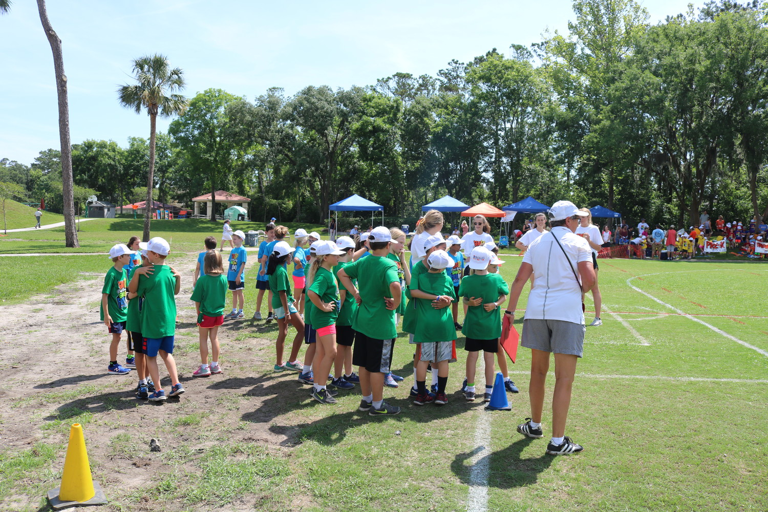 Bolles PVB students play a game at last week’s Field Day event in which they had to hug each other to hold a ball and carry it around a cone.