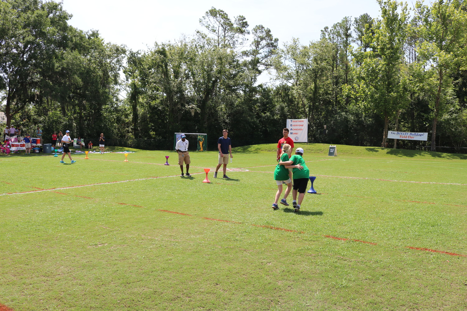 Bolles PVB students play a game at last week’s Field Day event in which they had to hug each other to hold a ball and carry it around a cone.