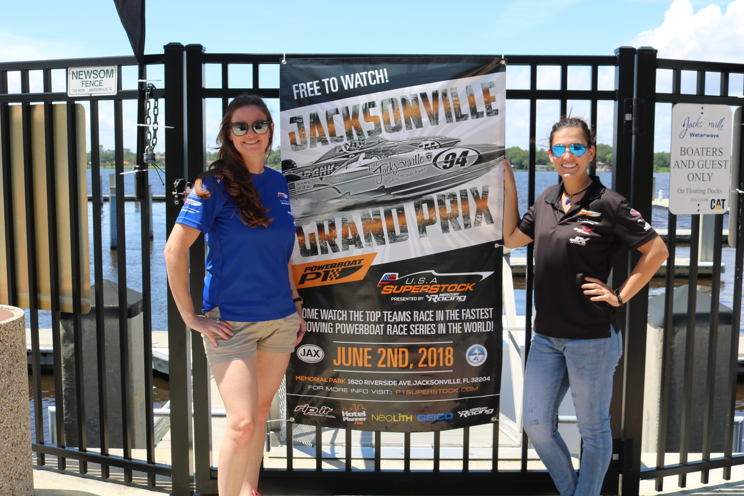 Powerboat P1 Head of Sponsorship and Marketing Lara Johnston poses for a photo with Marking Coordinator Marissa Thompson near a poster for the June 2 Powerboat P1 race in Jacksonville.