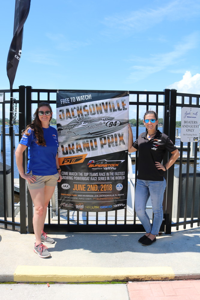 Powerboat P1 Head of Sponsorship and Marketing Lara Johnston poses for a photo with Marking Coordinator Marissa Thompson near a poster for the June 2 Powerboat P1 race in Jacksonville.
