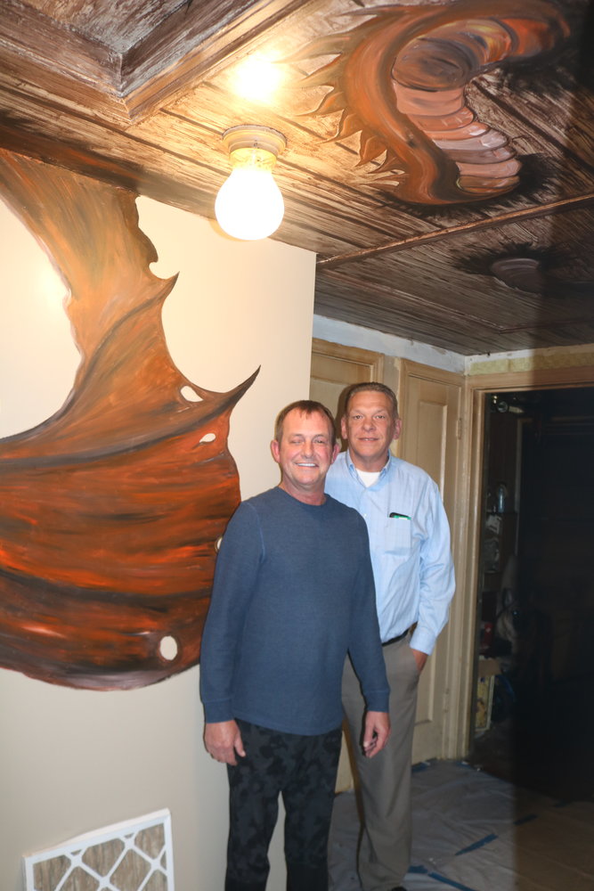 Hugh Tibbitts (left) and Tom Bright stand in front of their dragon hallway mural painted by Jerrod Brown.
