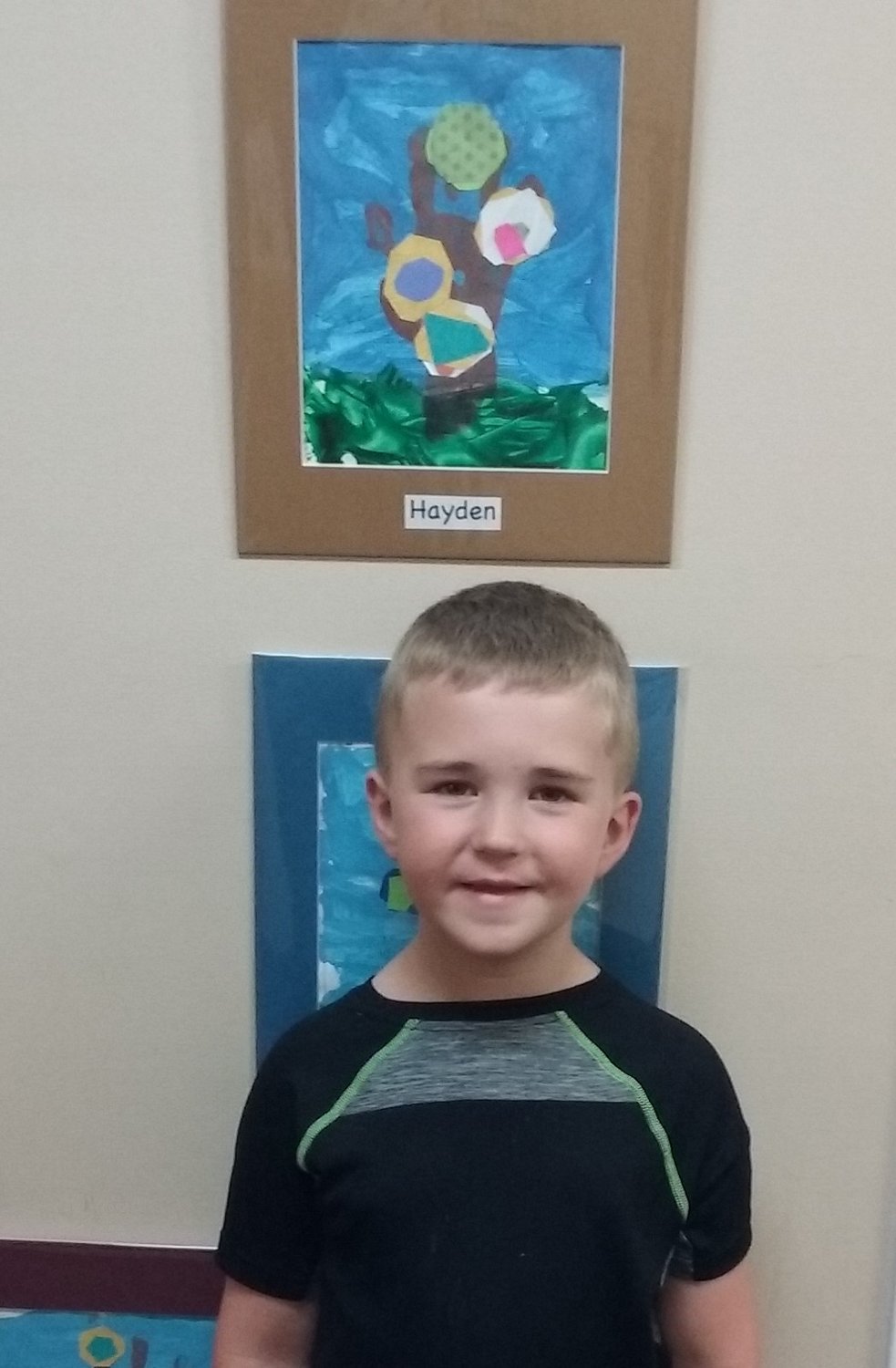 Hayden Westberg, 5, stands beneath his work of art for the Promisetown Preschool Art Show.
