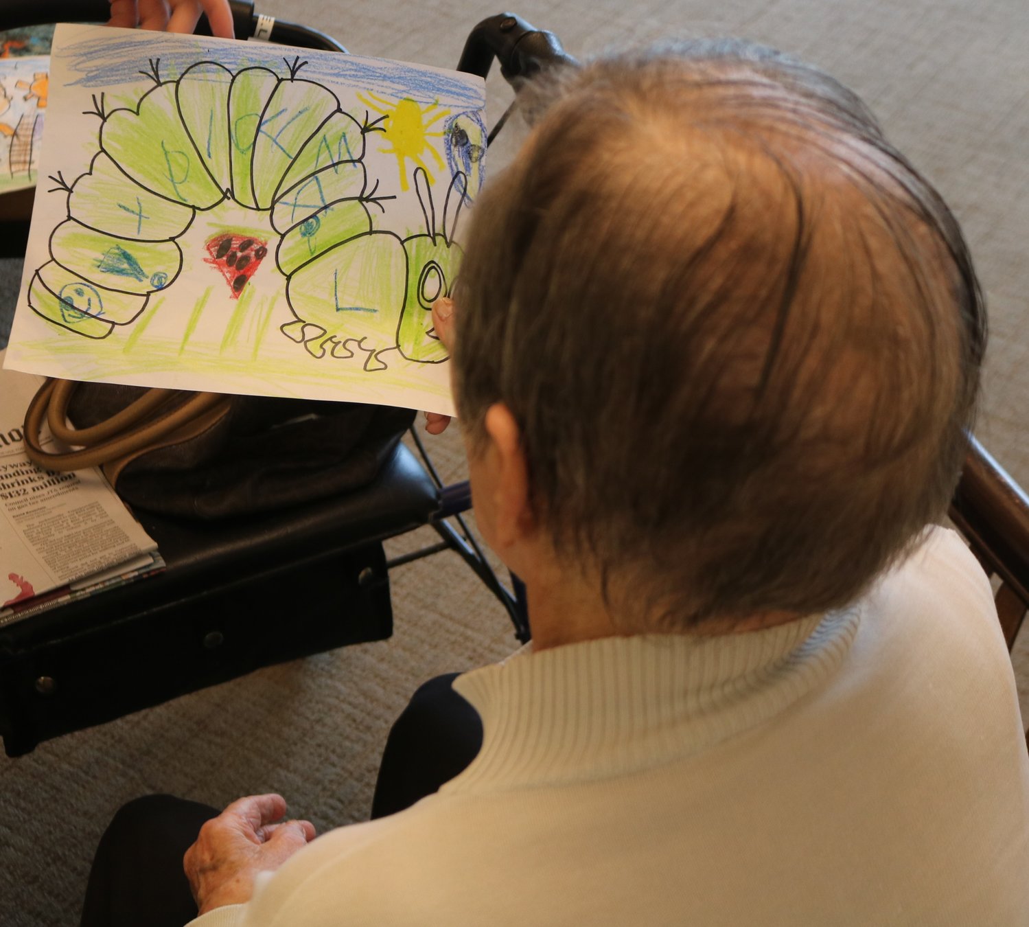 A resident of Ponte Vedra Gardens Alzheimer’s Special Care Center looks at a picture colored by a child.