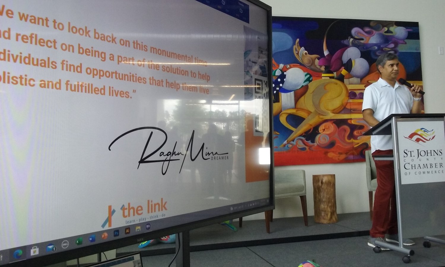 Entrepreneur Raghu Misra speaks during grand opening festivities for the link on Wednesday, July 14. The screen to the left displays a quote from Misra.