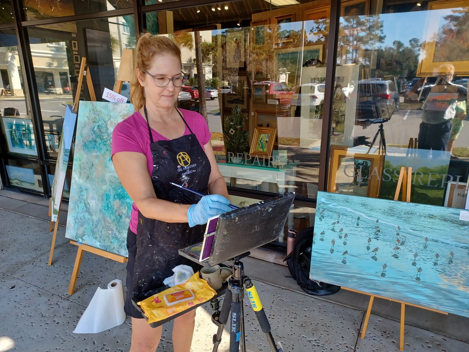 Artist Eve Albrecht conducts a painting demonstration outside Village Arts Framing and Gallery, during a holiday open house on Saturday, Dec. 11.