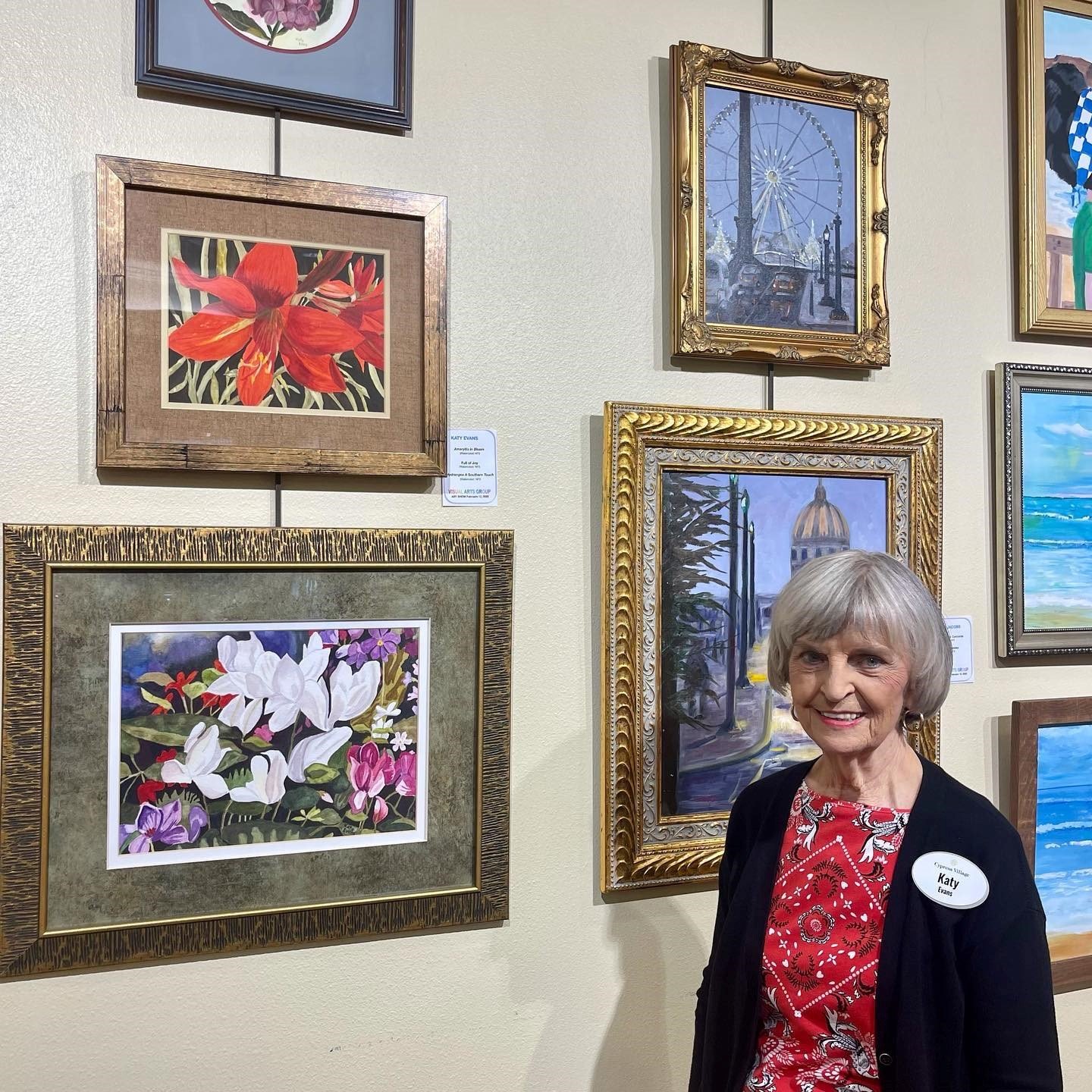 Artist Katy Evans stands next to some of her paintings at the Cypress Village Visual Arts Show.