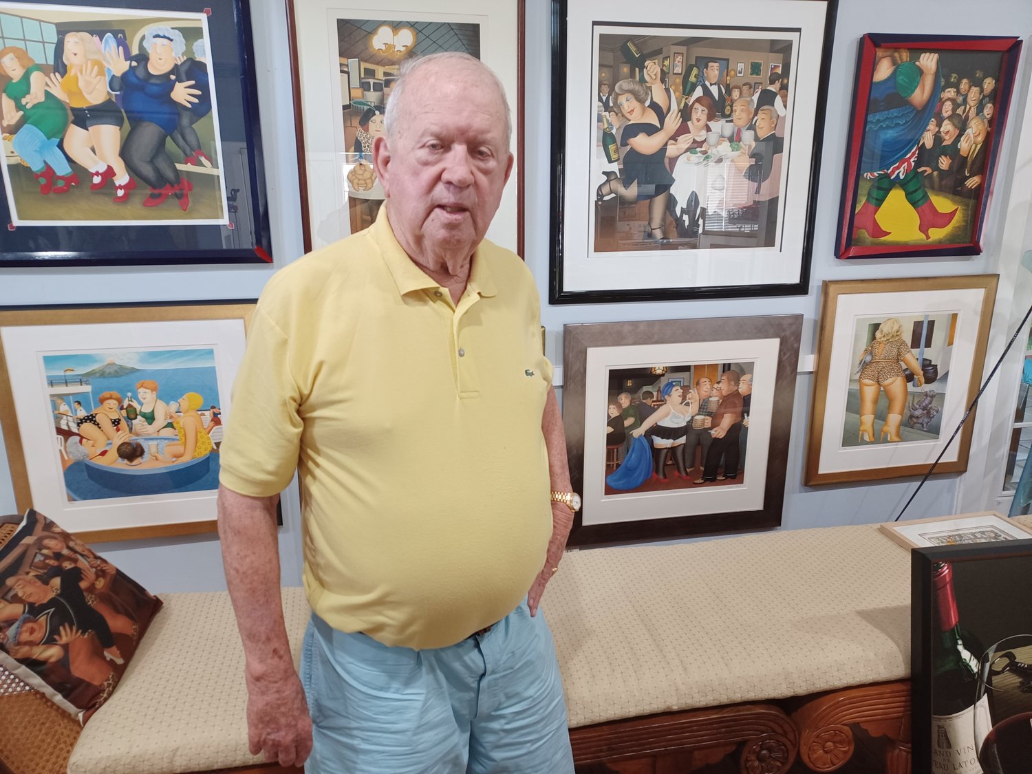 With original prints of Beryl Cook’s paintings behind him, J. Norman Henry stands in a room he has filled with art.