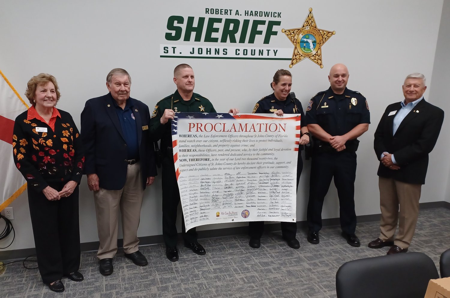 Pictured with the banner from left: We Can Be Heroes Foundation President Beth Heath, Veterans Council of St. Johns County Chair Bill Dudley, St. Johns County Sheriff Robert Hardwick, St. Augustine Police Chief Jennifer Michaux, St. Augustine Beach Police Chief Daniel Carswell, foundation officer Ron Birchall.