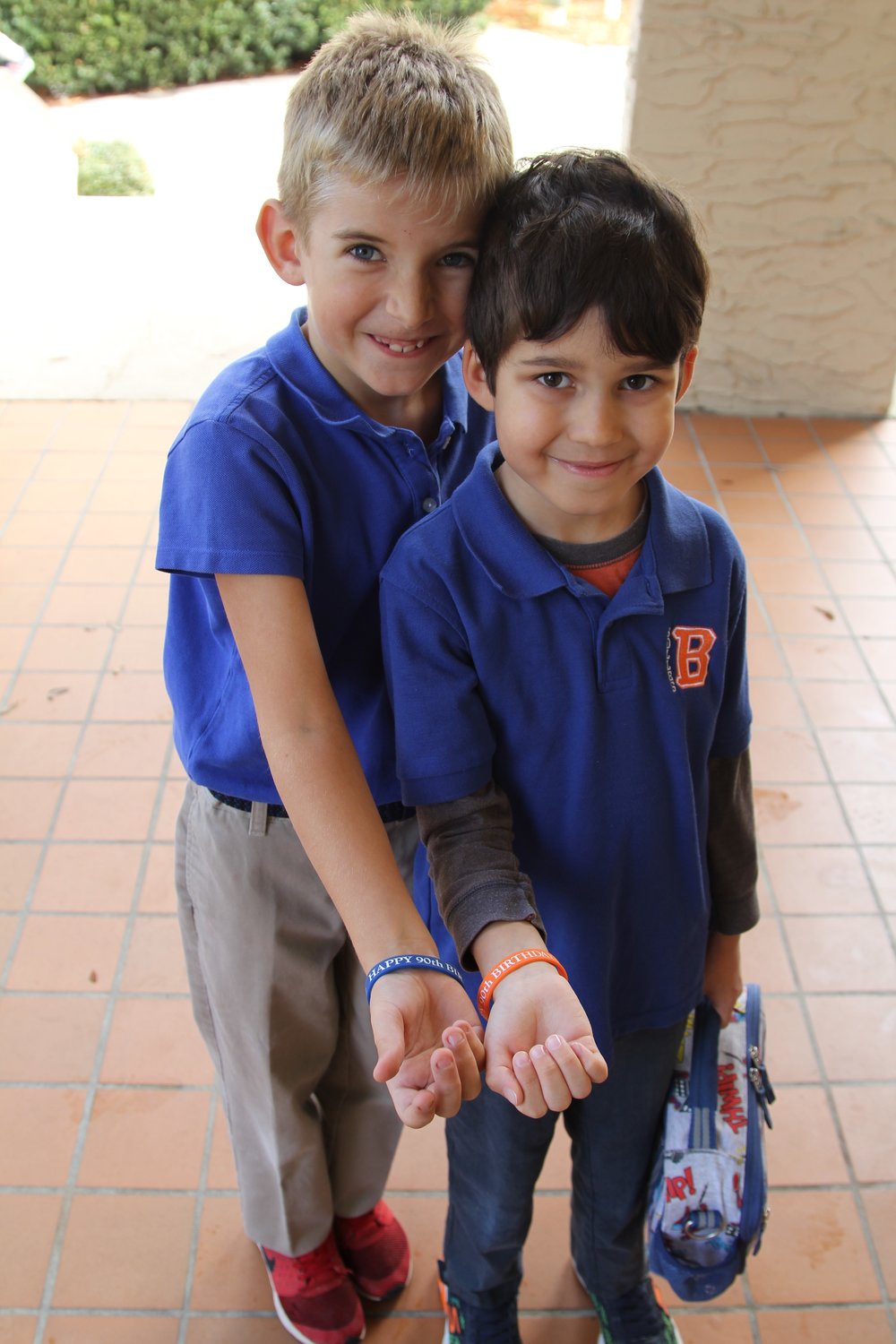 Two Bolles lower school students show off bracelets that read, “Happy 90th Birthday, Bolles.”